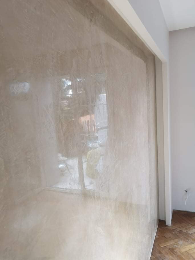 Detailansicht der polierten Wandfläche mit feinen Farbnuancen und sichtbaren Lichtreflexionen.