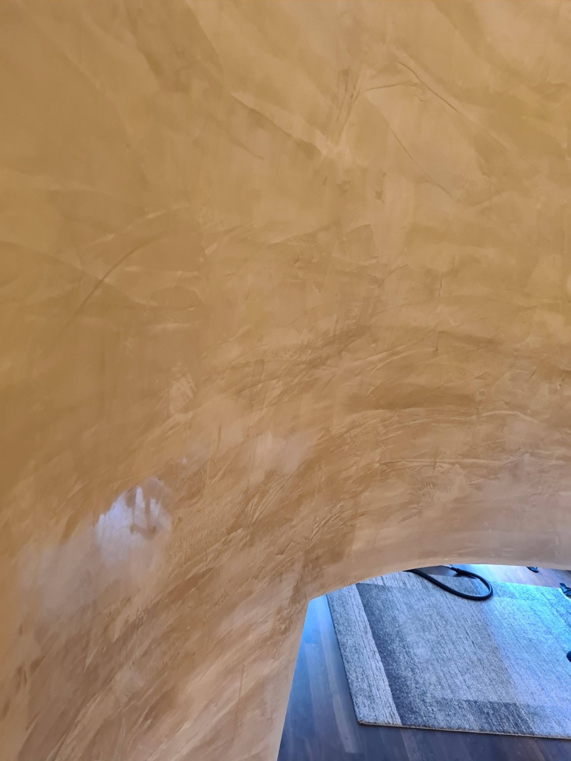 Stucco-Oberfläche an einer gerundeten Wandpartie mit warmer Farbgebung und lebendiger Struktur.