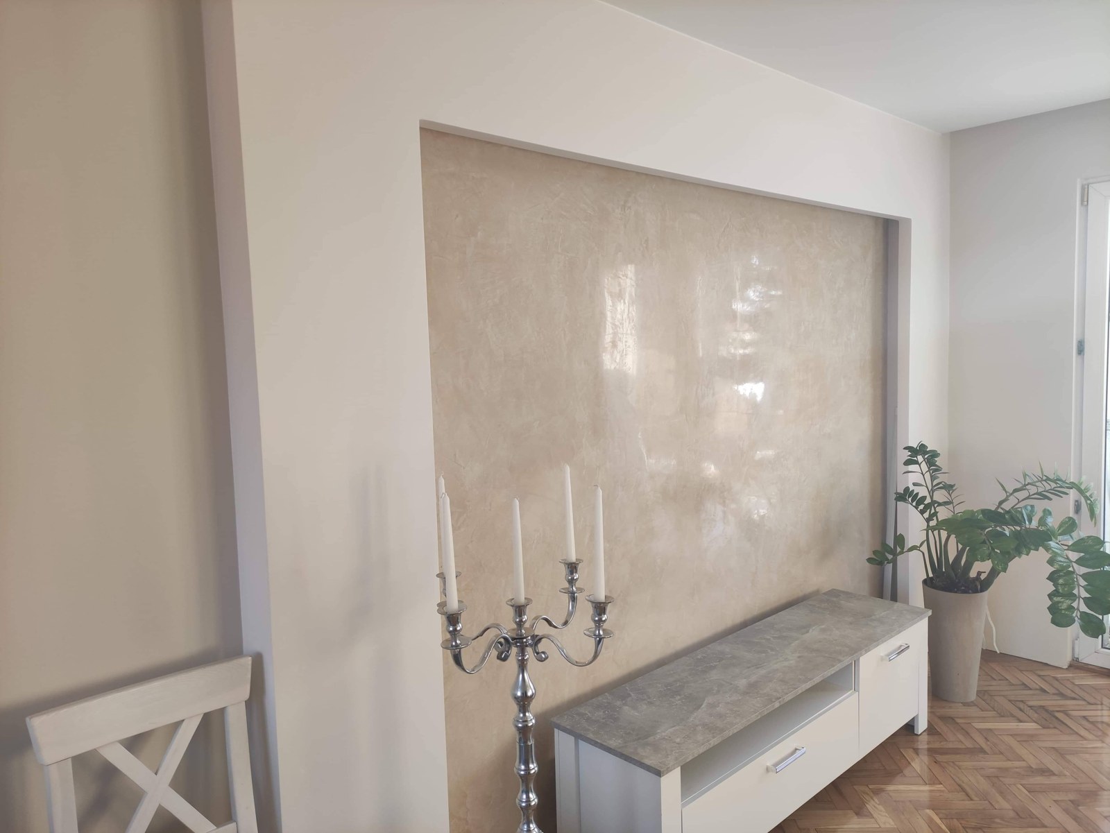 Cremefarbene Stucco-Oberfläche mit glänzender Marmoroptik innerhalb einer weissen Einfassung.